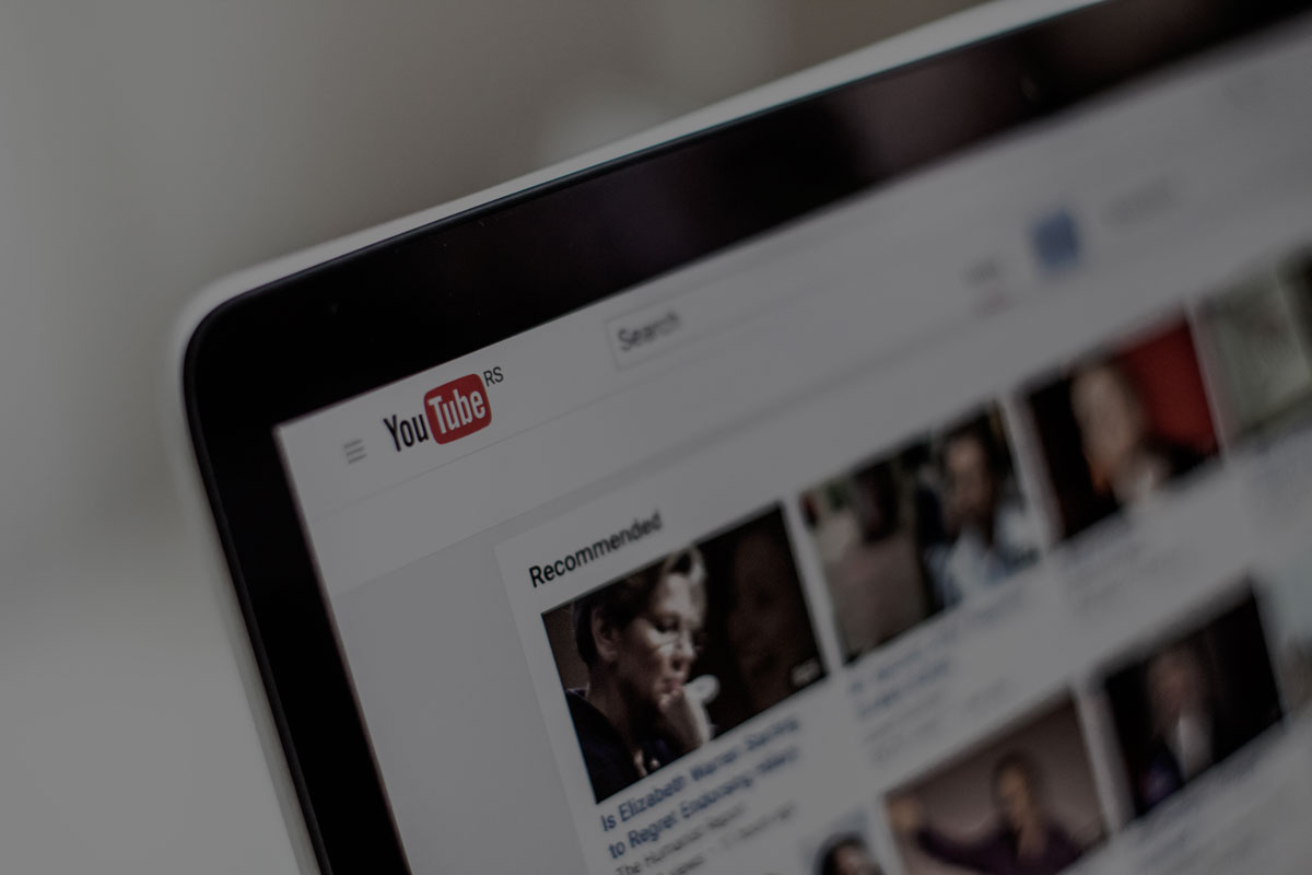 Angeschnittenes Bild eines Computerbildschirms. Darauf ist die Webseite von YouTube zu erkennen. Das ganze Bild ist leicht verdunkelt.
